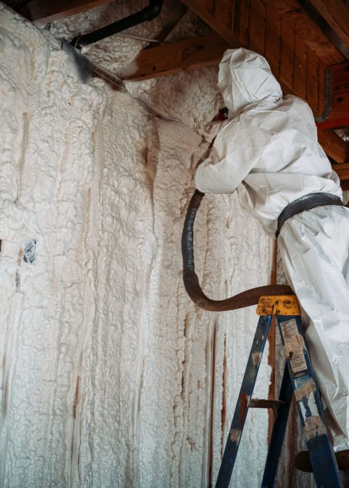 A worker doing spray foam insulation on the walls